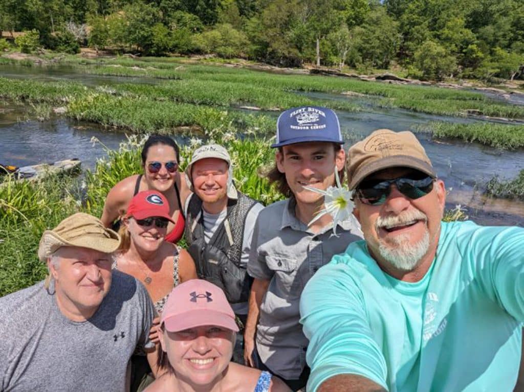 group of smiling people at a river