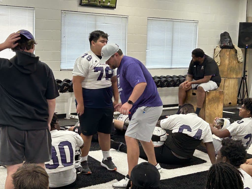 coach with players in high school football training room