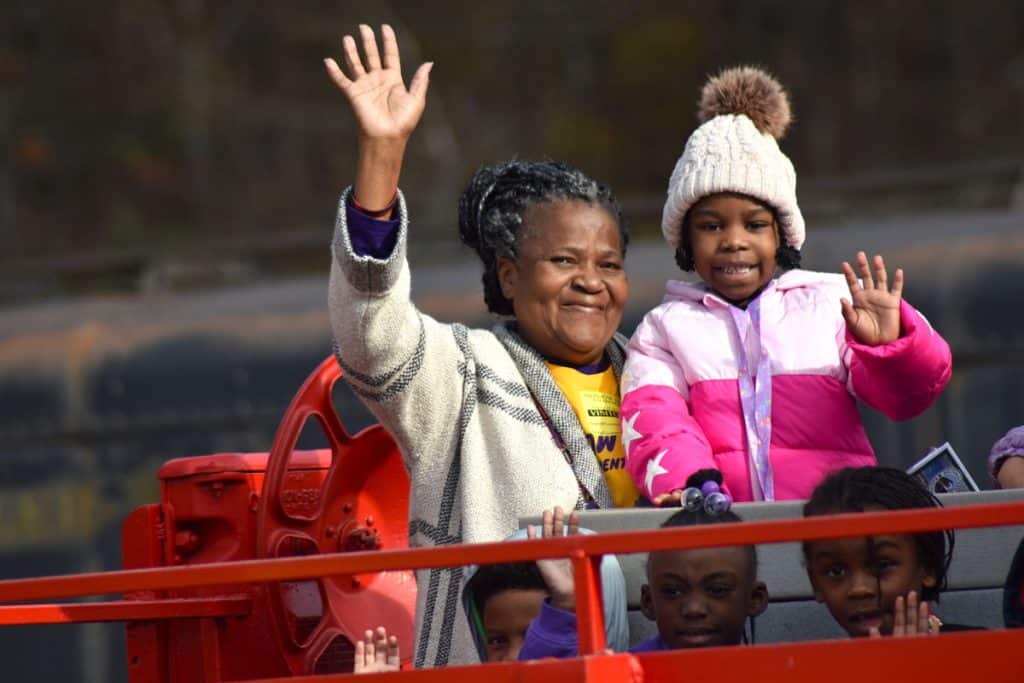 An adult woman and child waving as they ride on a train at an outdoor private event