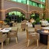 Outdoor dining space with tables, chairs and strings of lights at dusk