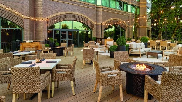 Outdoor dining space with tables, chairs and strings of lights at dusk