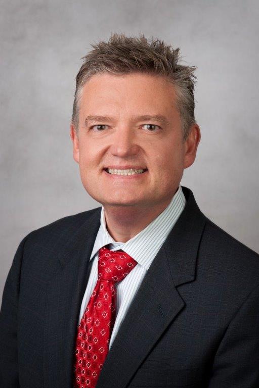 Headshot of man in a suit smiling and looking at camera