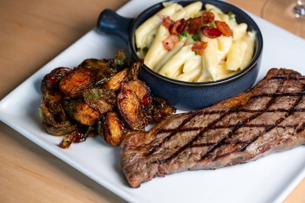 Grilled steak with two sides on a white plate