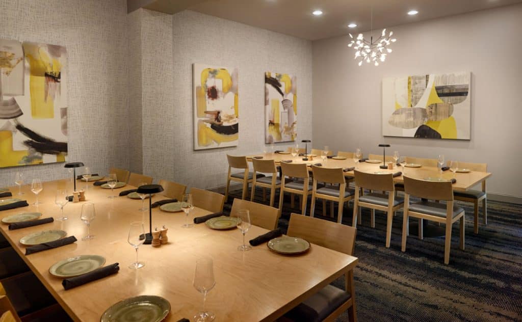 Private restaurant dining room with two long tables and place settings for 24