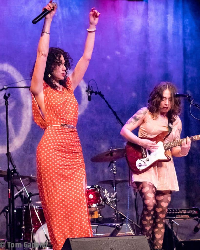 Two female musicians rocking out on stage