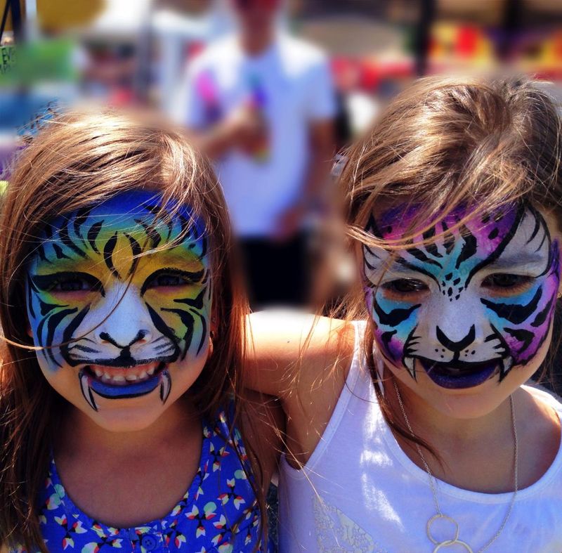 Two girls with face paint at an outdoor arts festival