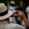 person in a hat taking a photo with a cell phone