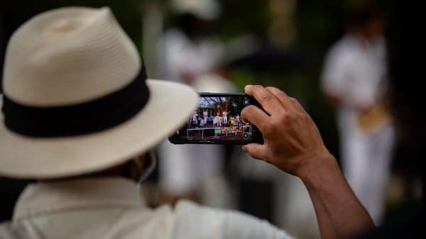 person in a hat taking a photo with a cell phone