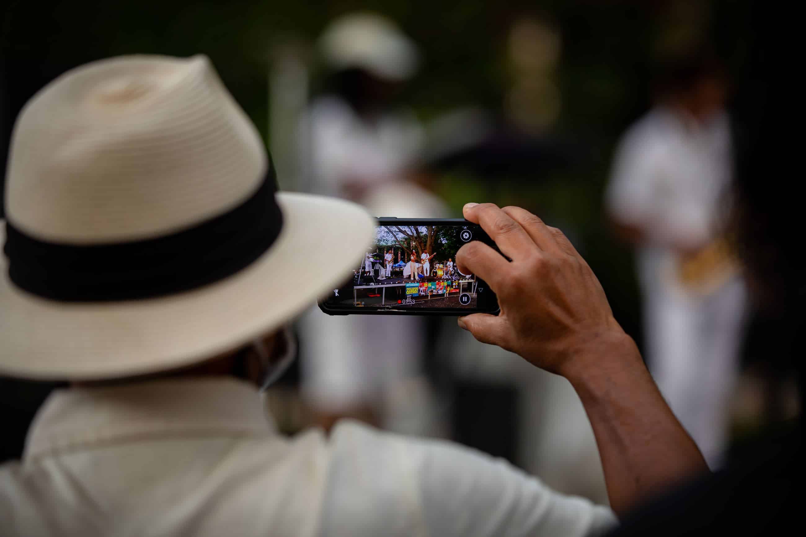 person in a hat taking a photo with a cell phone