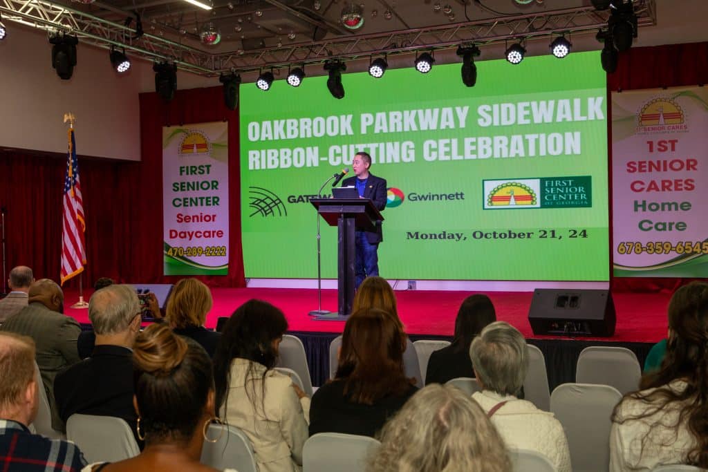 Man speaking to a crowd at a ribbon-cutting ceremony