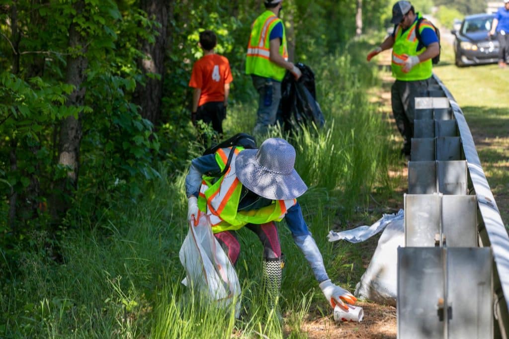 volunteers picking up trash along a wooded road