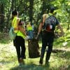 people carrying away trash cleaned up from a wooded area