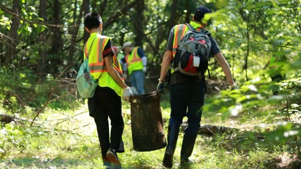 people carrying away trash cleaned up from a wooded area