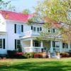 exterior view of historic white house with red roof and green grass and trees