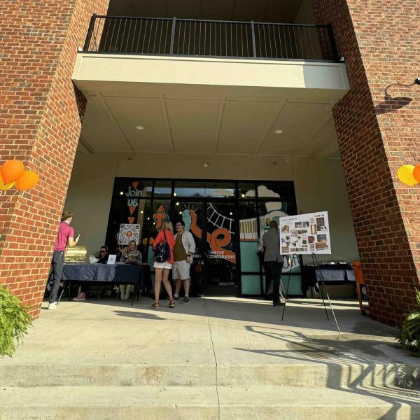 Exterior of two story office building with signs, balloons and few people in front for a grand opening party