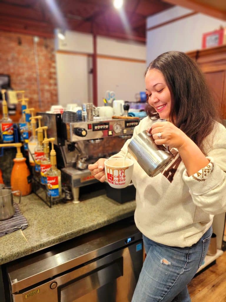 Woman pouring cream into a pumpkin latte at a cafe