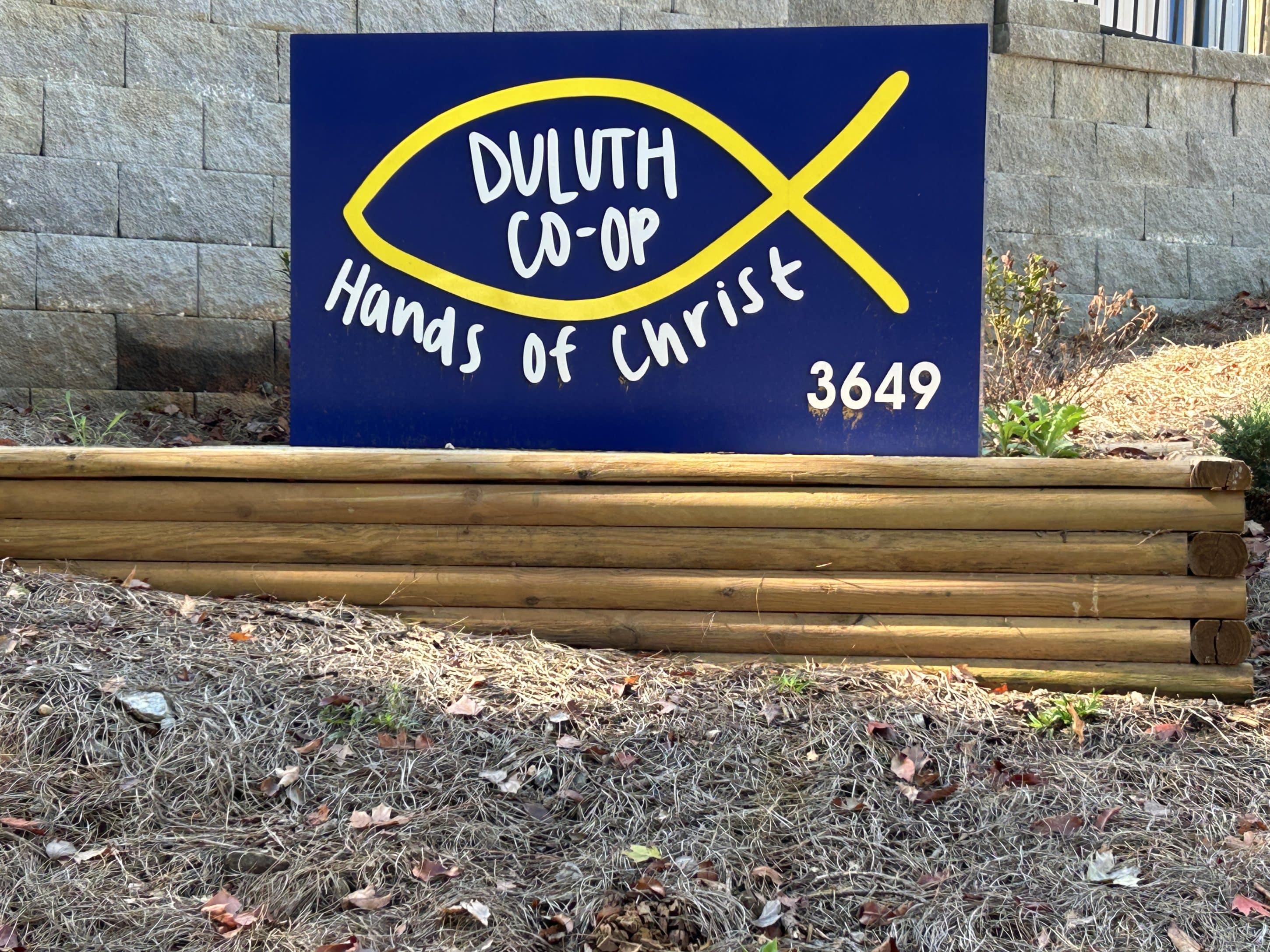 blue and yellow sign with the Christian fish symbol and the name Duluth Co-op