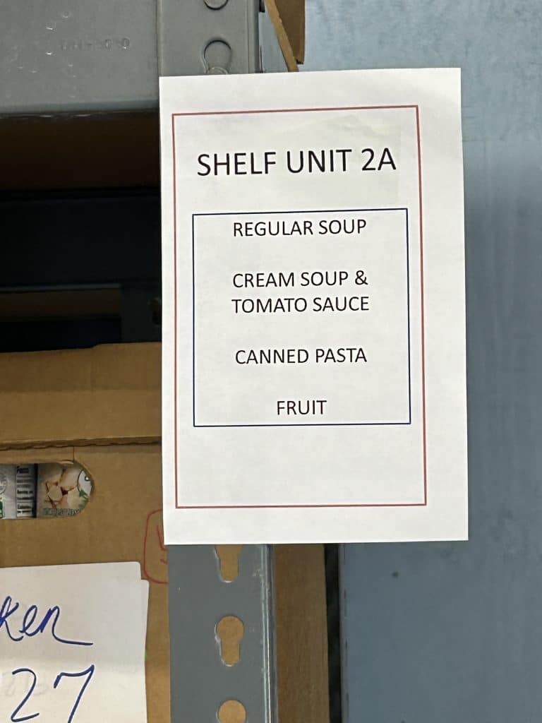 sign on a food pantry shelf listing what items are stored there