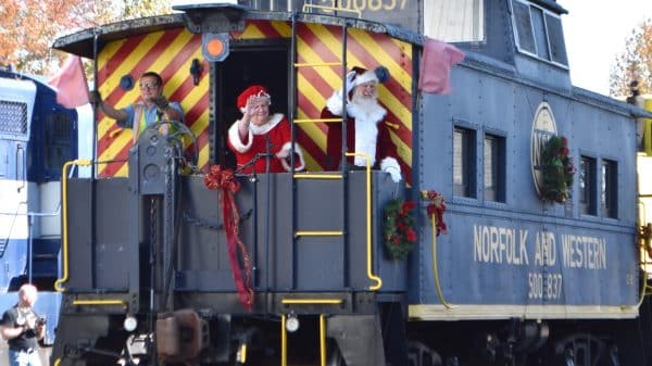 Santa and Mrs. Claus waving from a train caboose