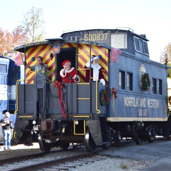 Santa and Mrs. Claus waving from a train caboose