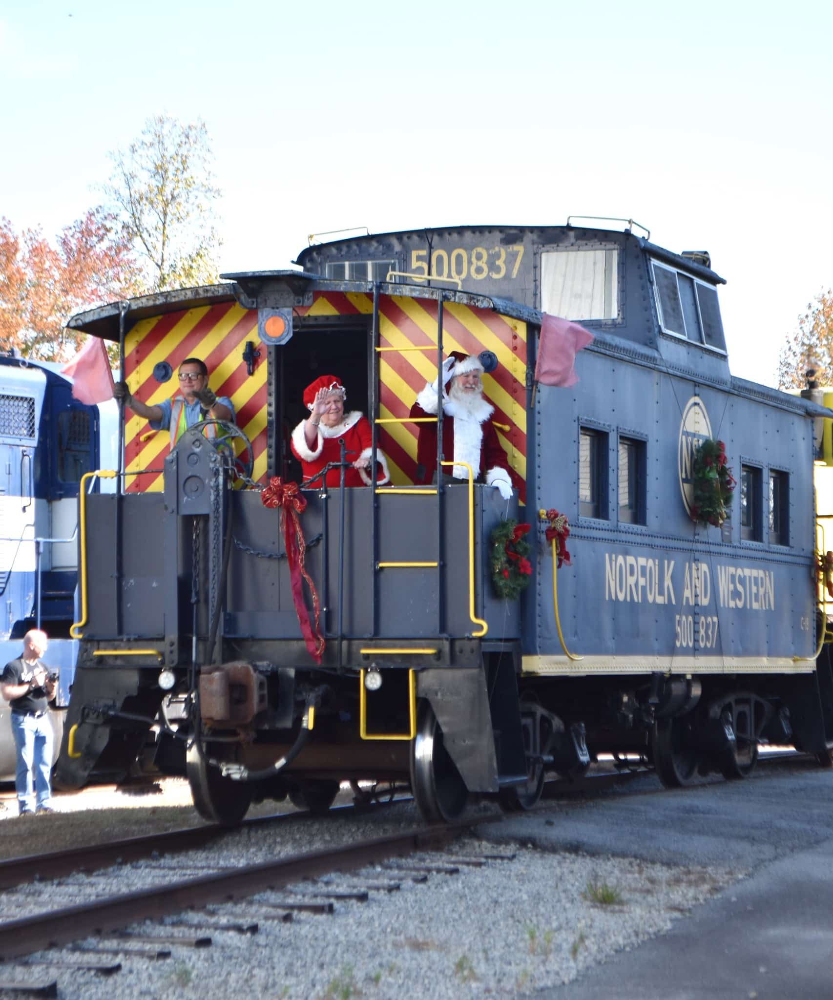 Santa and Mrs. Claus waving from a train caboose