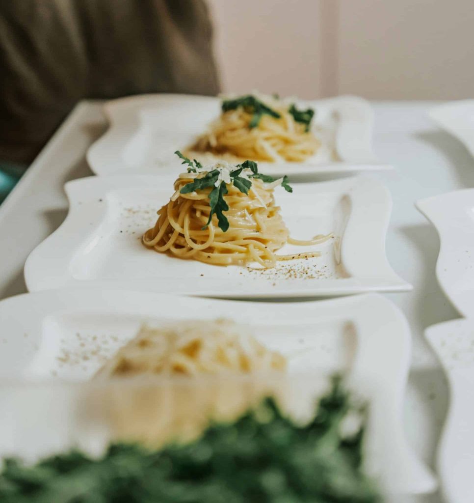 Three plates of cacio e pepe lined up on a counter