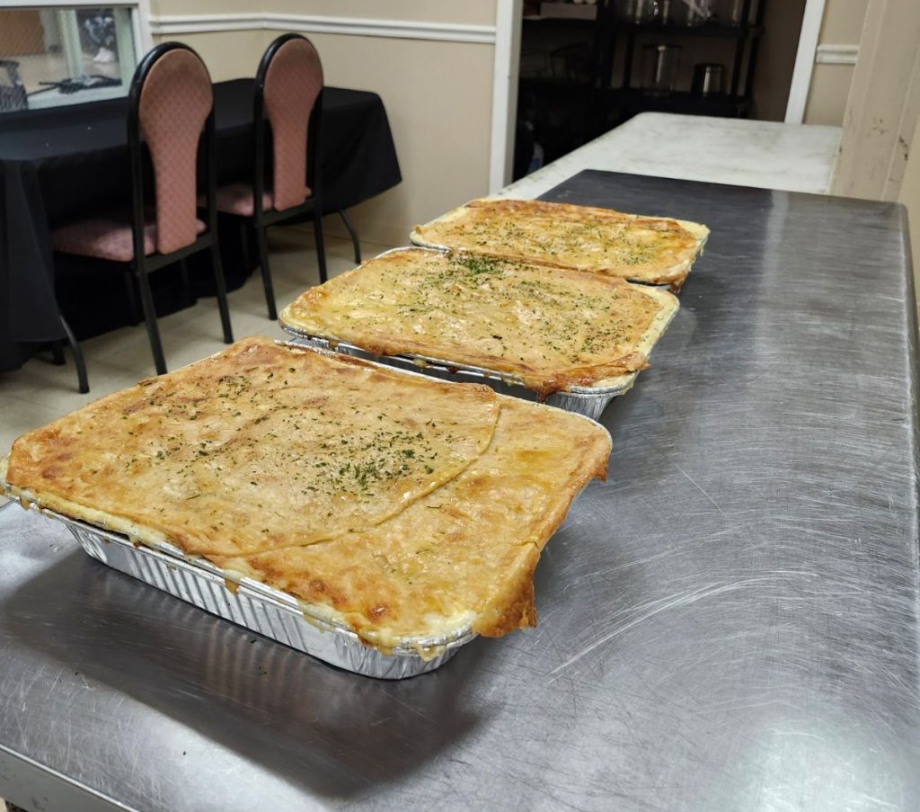 Three large pans of chicken pot pie sitting on a metal kitchen counter