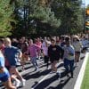 Group of middle school kids running on a track with green trees behind them