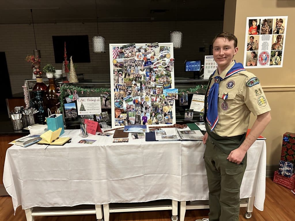 Young white high school student and Eagle Scout, standing in uniform in front of a display.