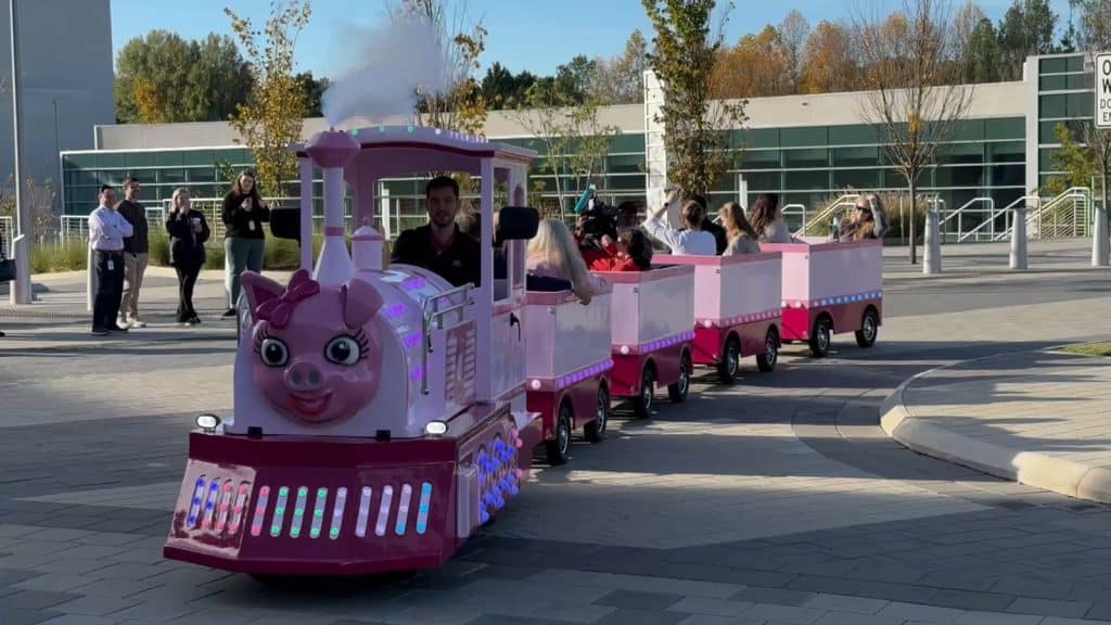 Guests riding on a pink pig trackless train