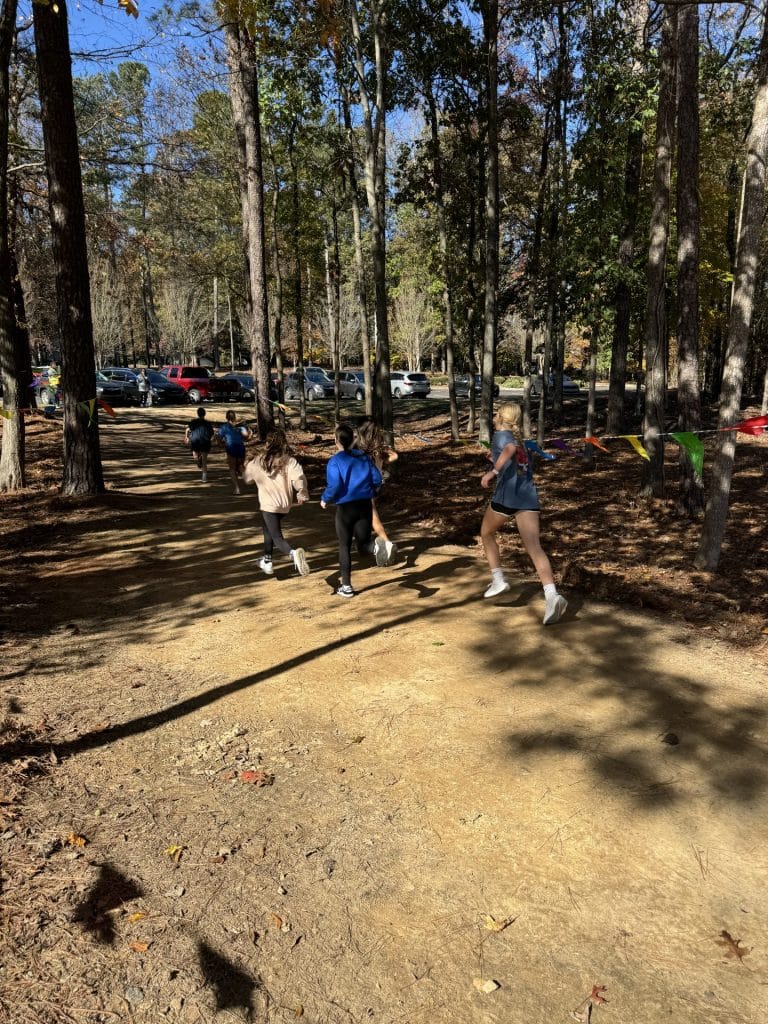 Middle school kids running along an unpaved, wooded path during Turkey Trot 2024