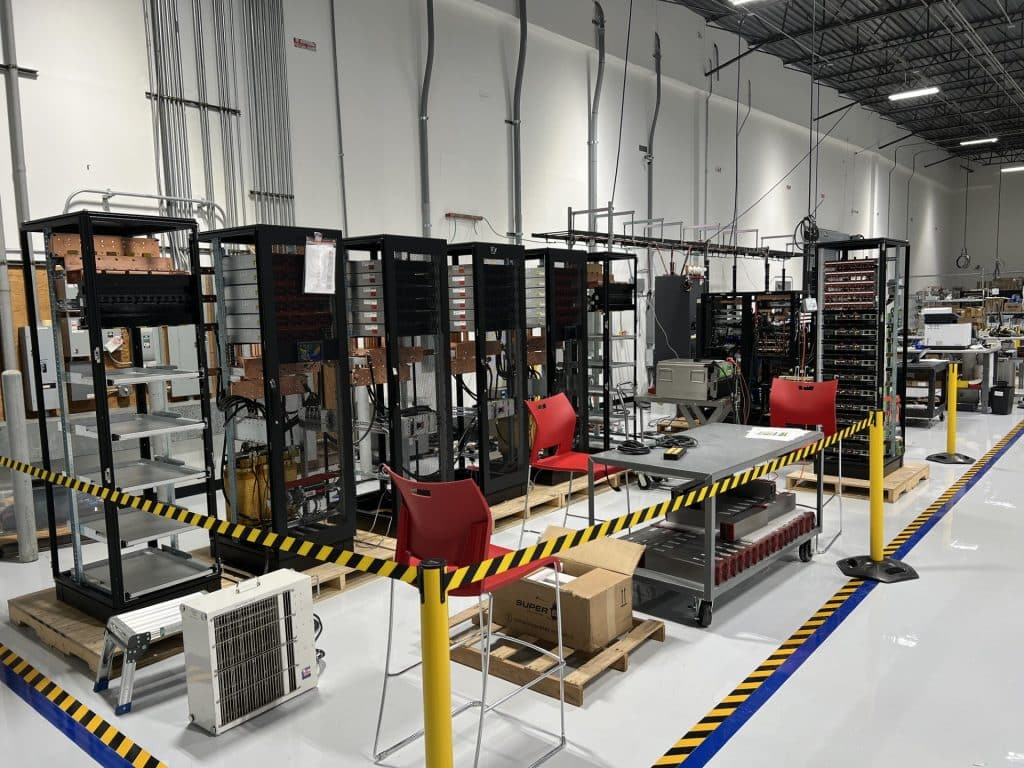 Interior of a very clean, state-of-the-art manufacturing facility with equipment and office chairs behind yellow and black tape