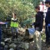 a group of students studying water quality in a small stream in a wooded area