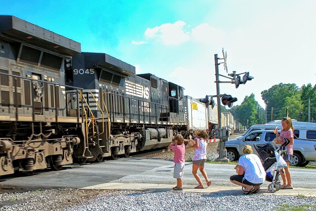 Two kids cheering the train going past a crossing in Norcross