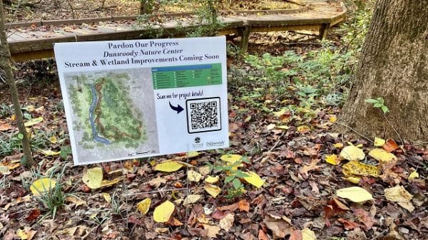 Small sign on the ground at a nature center informing about improvements being made to the park