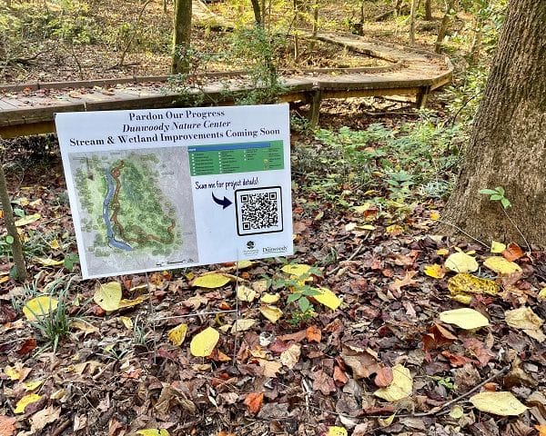 Small sign on the ground at a nature center informing about improvements being made to the park