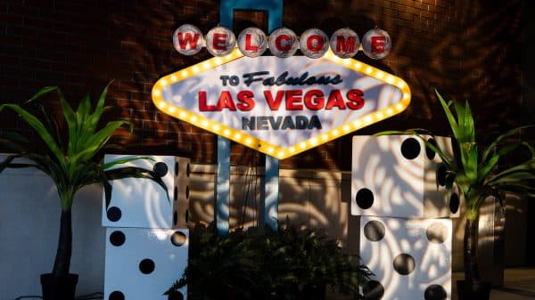 Replica of the famous Las Vegas sign alongside plants and giant dice at a Las Vegas-themed event.