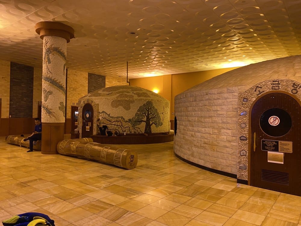 Interior of Jeju Sauna with stone sauna rooms and warm, yellow/gold lighting.