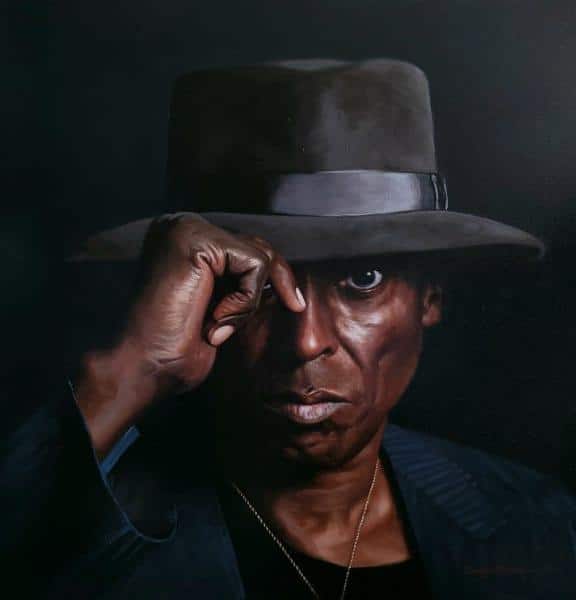 Realist-style painting of Miles Davis by Dwayne Mitchell. The colors are dark and muted and the image shows Davis in a hat, with hand reaching up to touch the brim.