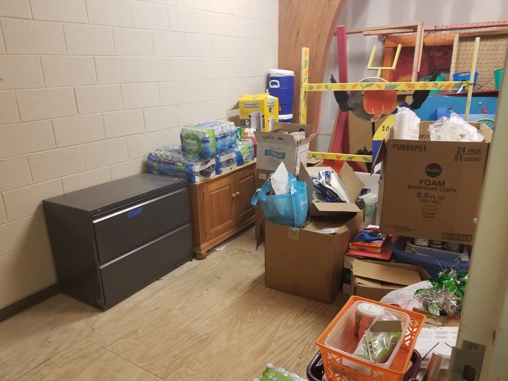 A disorganized storage room with boxes and bags on the floor.