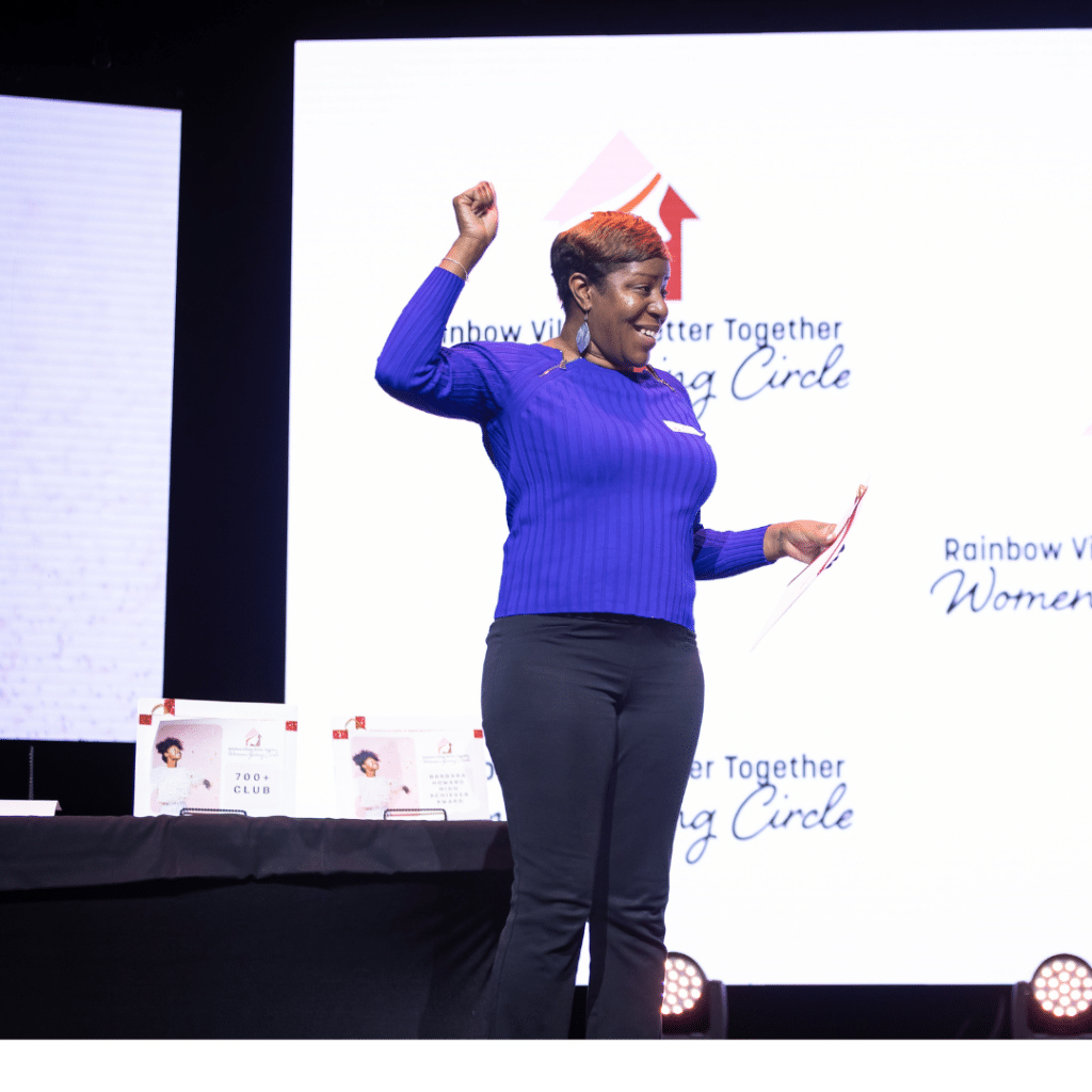 A woman in a blue sweater and black pants receiving a financial award at a community event