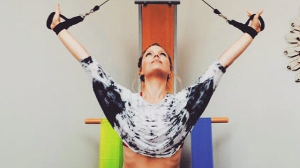 Woman with hair pulled back in ponytail, looking up towards the ceiling, using stretch bands at a small wellness center.