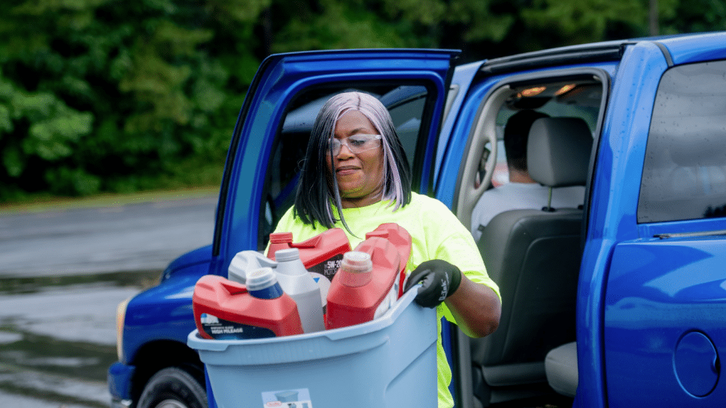 Volunteer hauling a bin of household hazardous waste from a participants vehicle at a HHW drop off event in Gwinnett County.