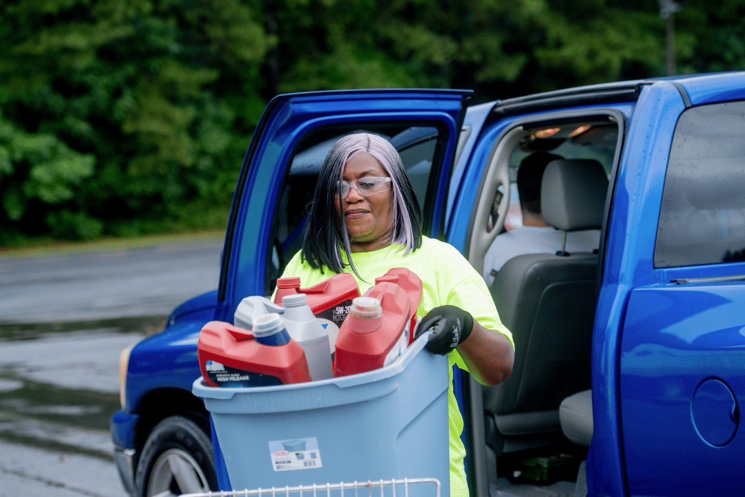 Volunteer hauling a bin of household hazardous waste from a participants vehicle at a HHW drop off event in Gwinnett County.