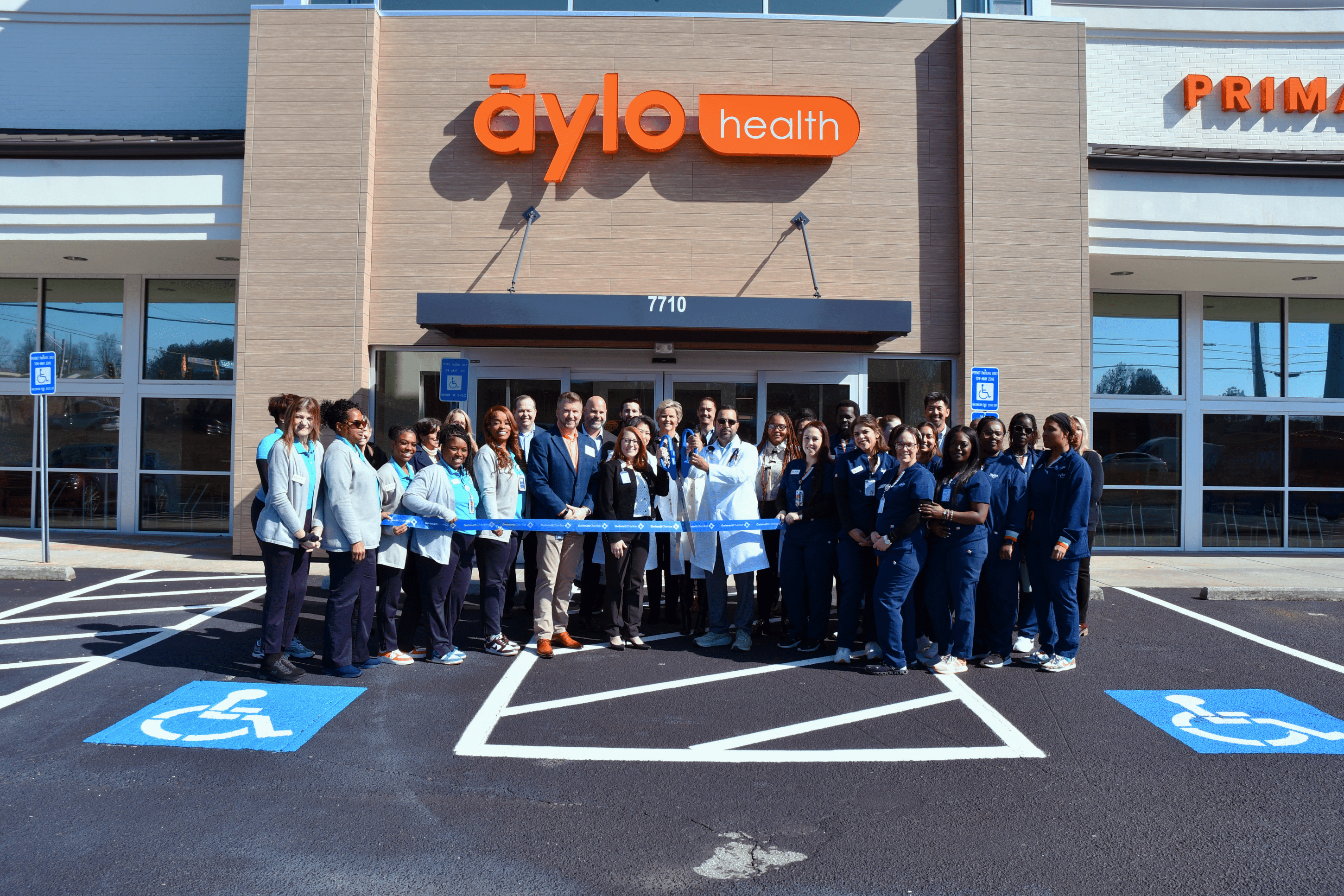 Group of people in a parking lot at a ribbon cutting for Aylo Health in Suwanee, GA.