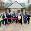 A group of people outdoors at a ribbon cutting ceremony for SaveStations in city parks