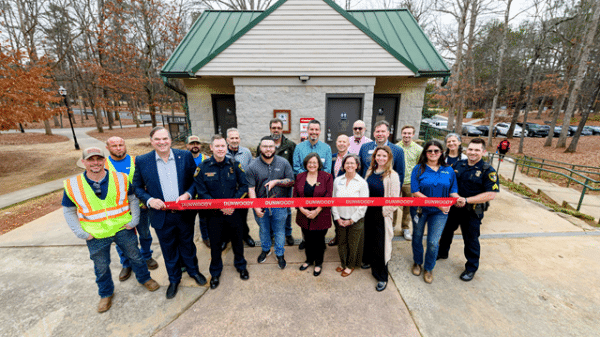 A group of people outdoors at a ribbon cutting ceremony for SaveStations in city parks