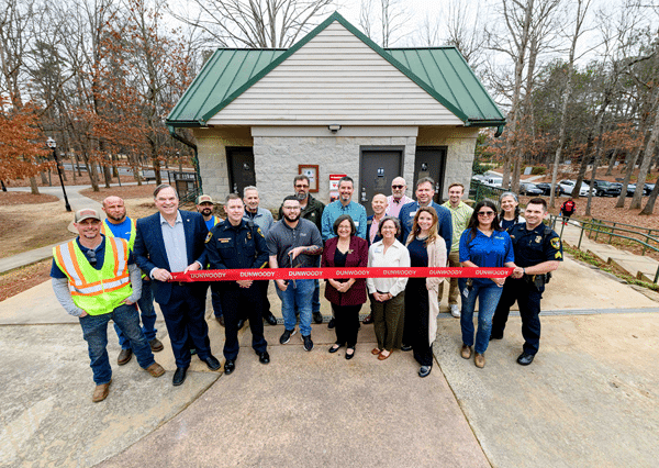 A group of people outdoors at a ribbon cutting ceremony for SaveStations in city parks