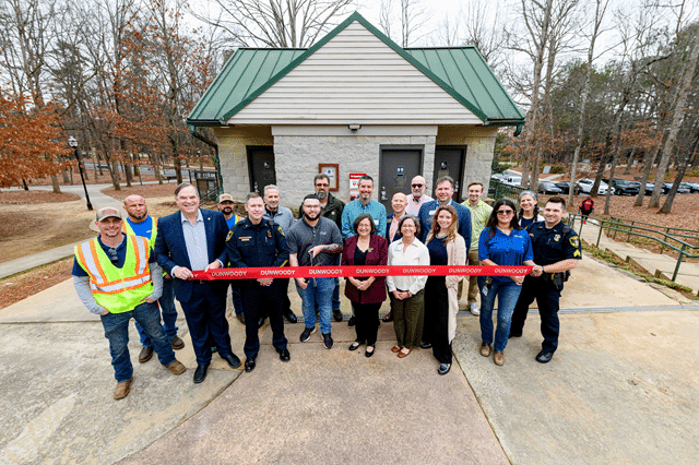 A group of people outdoors at a ribbon cutting ceremony for SaveStations in city parks