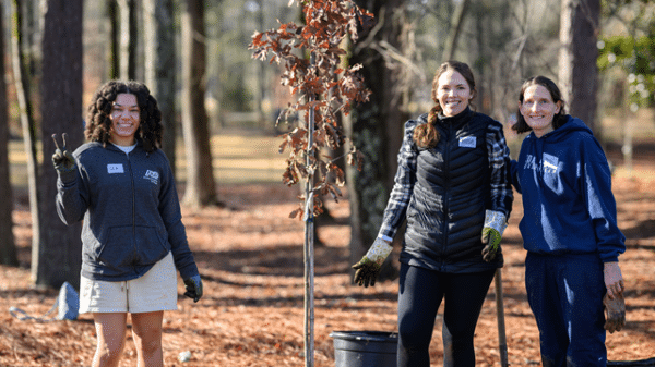 Three young women in a wooded area planting trees with City of Dunwoody on MLK Day of Service 2025.